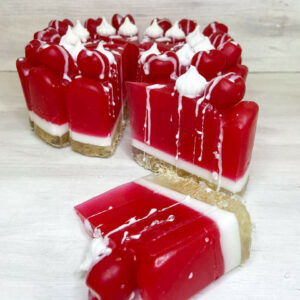 Χειροποίητη τούρτα σαπουνιού σε μορφή cheesecake με αποχρώσεις κερασιού και λευκού, διακοσμημένη με ρεαλιστικά στοιχεία και έντονο άρωμα κερασιού.